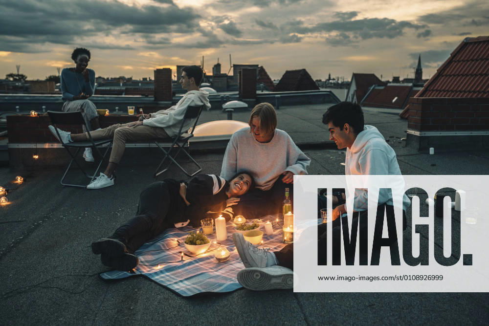 Male and female friends talking on building terrace during sunset Germany, Berlin, model released, property released