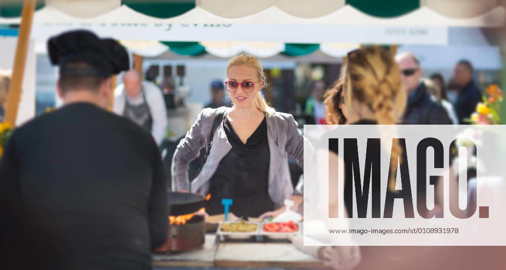 Woman buying meal at street food festival. Beautiful blonde caucasian lady buying freshly prepared meal at a local street food festival. Urban international kitchen event in Ljubljana, Slovenia, in summertime., model releasedwoman, food, market, grill, barbecue, street, people, young, shop, beautiful, healthy, outdoors, festival, fresh, lady, customer, urban, female, city, face, drink, stall, european, buy, vegetable, person, lifestyle, produce, attractive, summer, beverage, purchase, organic, portrait, marketplace, tourism, tourist, event, market stall, market stand, leisure, buying, stand, juise, sunglasses, cook, hat, casual, crowd, look,
