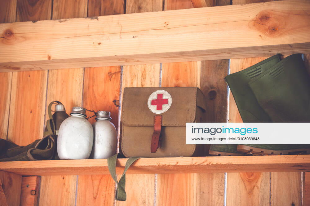 Retro medic equipment on an old wooden shelfe Retro medic equipment on an old wooden shelfe with boots and water bottlesmedic, medical, kit, health, first, medicine, military, symbol, red, old, equipment, bag, aid, army, emergency, cross, doctor, care, object, texture, white, weathered, combat, war, help, boots, detail, ambulance, water, grunge, fabric, supplies, background, travel, injury, jute, hurt, accident, pharmacy, rustic, safety, treatment, insurance, hospital, rescue, healthcare, wood, shelfe, vintage, retro,