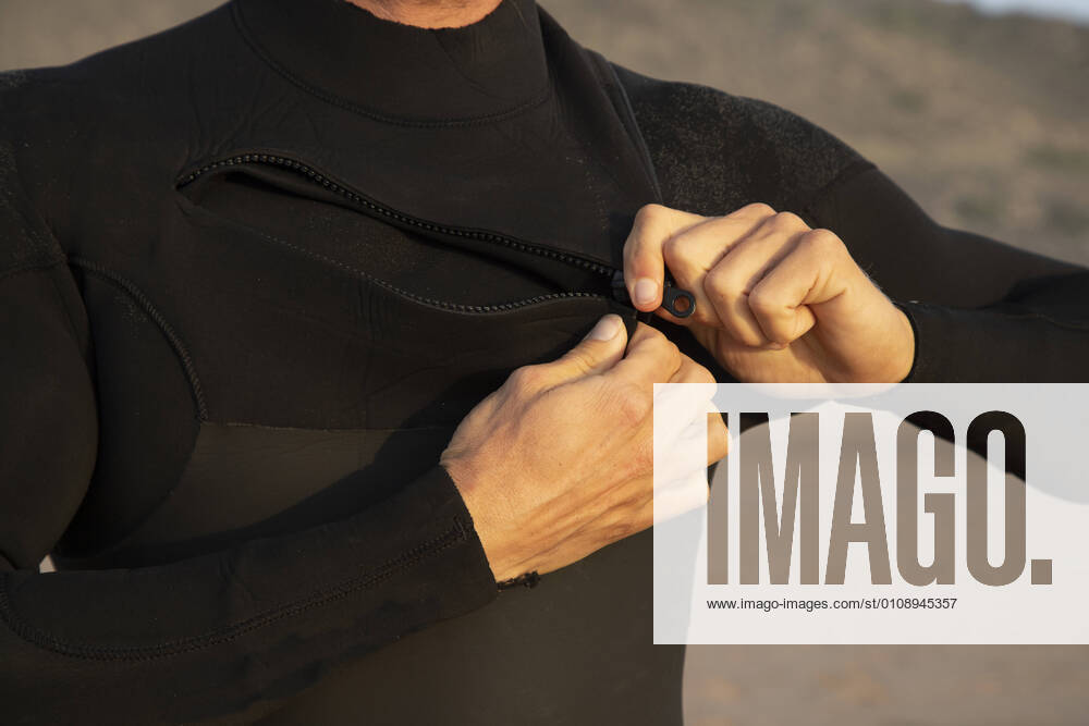Man zipping black wetsuit at beach model released Symbolfoto KBF00630