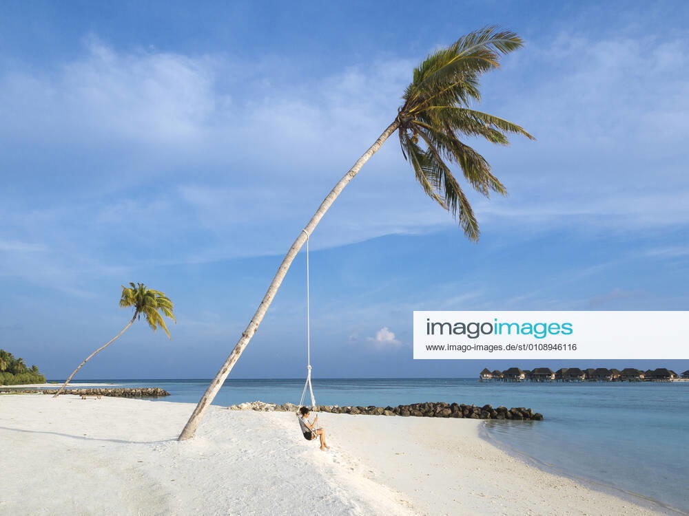Woman swinging on rope against sea at beach, Bali model released Symbolfoto KNTF06010
