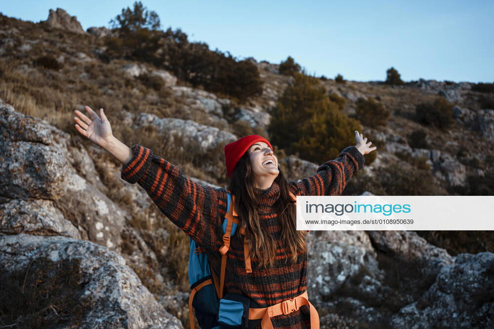 Happy woman with arms outstretched standing on mountain during vacation model released Symbolfoto RCPF00425