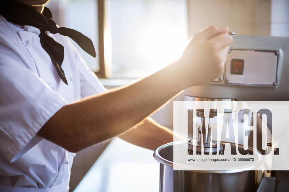 IMAGO Creative: Haushaltsgeräte - Küchenmaschine Mid section of chef blending the batter in mixing blender Mid section of chef in commercial kitchen blending the batter in mixing blender, model released30s, Mid Adult, Man, Male, Caucasian, Chef, Chefs Whites, Head Chef, Uniform, Profession, Professional, Occupation, Job, Worker, Standing, Mixing, Blending, Bake, Baking, Batter, Mixer, Service, Expertise, Hospitality, Preparation, Mid Section, Indoors, Looking At Camera