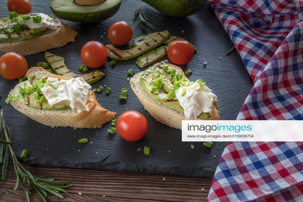 Bread with slices of avocado and cream cheese Bread with slices of grilled avocado and cream cheese on a black cutting stone board. Fresh parsley and rosemary. Vegetarian, vegan concept.avocado, toast, cream, cheese, food, bread, sandwich, green, white, healthy, fruit, meal, vegetable, snack, gourmet, lunch, breakfast, appetizer, delicious, natural, fresh, health, diet, tasty, dinner, vegetarian, slice, eating, tomato, raw, burger, butty, calories, cooking, dark, dietary, dietetic, genetically, organic, seasonal, seeds, spoon, spring, summer, vegan, vegetables,