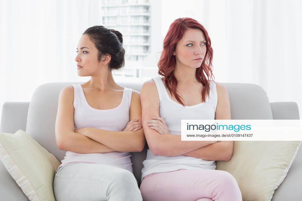 Unhappy friends not talking after argument at home Unhappy young female friends not talking after argument at home on the couch, model released, property released