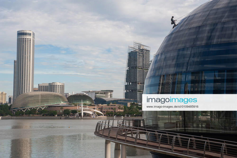 Singapur, Republik Singapur, Asien - Ein Arbeiter verrichtet Wartungsarbeiten an der kuppelfoermigen Glasfassade des neuen Apple-Vorzeigegeschaefts (Flagshipstore) am Ufer in Marina Bay Sands. Die futuristische Architektur des modernen Einzelhandelsgeschaefts hat die Form einer riesigen Glaskugel, die auf dem Wasser schwebt und ist der dritte Apple Store im suedostasiatischen Stadtstaat. Entworfen wurde das Gebaeude vom englischen Star-Architekten Sir Norman Foster (Foster and Partners). Die schwer vom Handel abhaengige Wirtschaft der Finanzmetropole erlitt im letzten Jahr auf Grund der Corona-Pandemie die schlimmste Rezession in ihrer jungen Geschichte und verzeichnete einen Rueckgang des BIP um 5,8 Prozent.