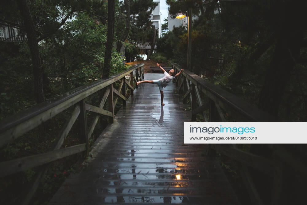IMAGO Creative: Ende des Sommers A graceful child dances in lamplight on rainy boardwalk at night Bethany Beach, DE, United States CR_RETI210106-479818-01 ,model released, Symbolfoto