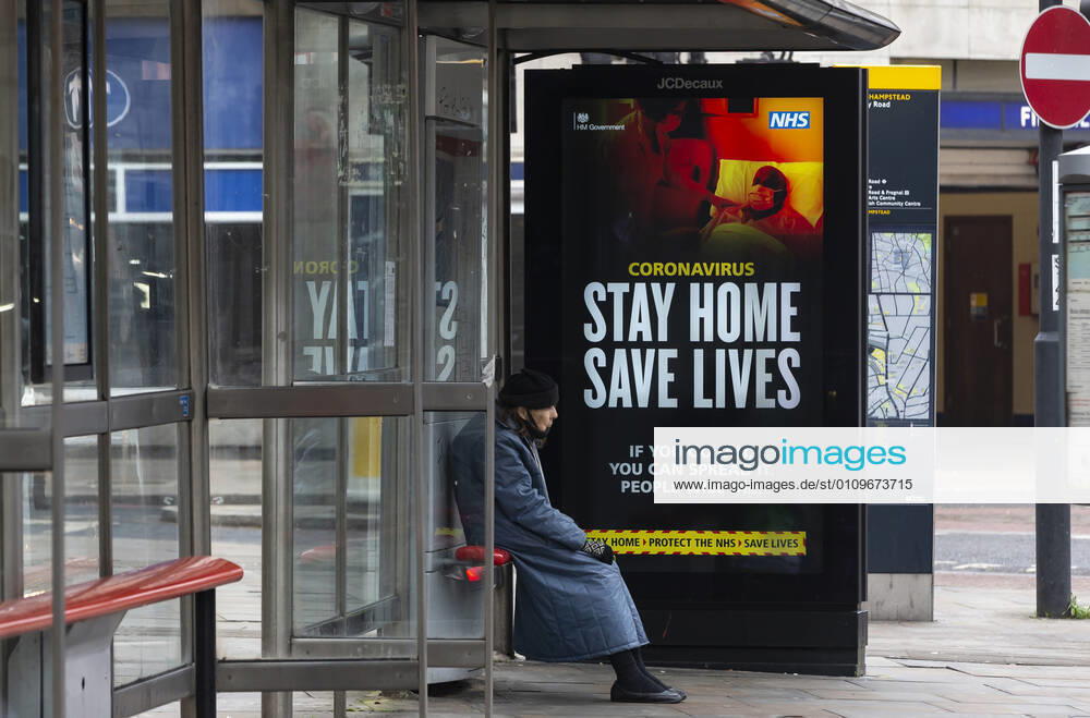 (210110) -- LONDON, Jan. 10, 2021 -- A person wearing a face mask sits next to an advertising board reading Stay Home Save Lives at a bus stop in London, Britain, Jan. 10, 2021. The coronavirus-related deaths in Britain surpassed 80,000 on Saturday with another 1,035 reported in the country. ) BRITAIN-LONDON-COVID-19-CASES HanxYan