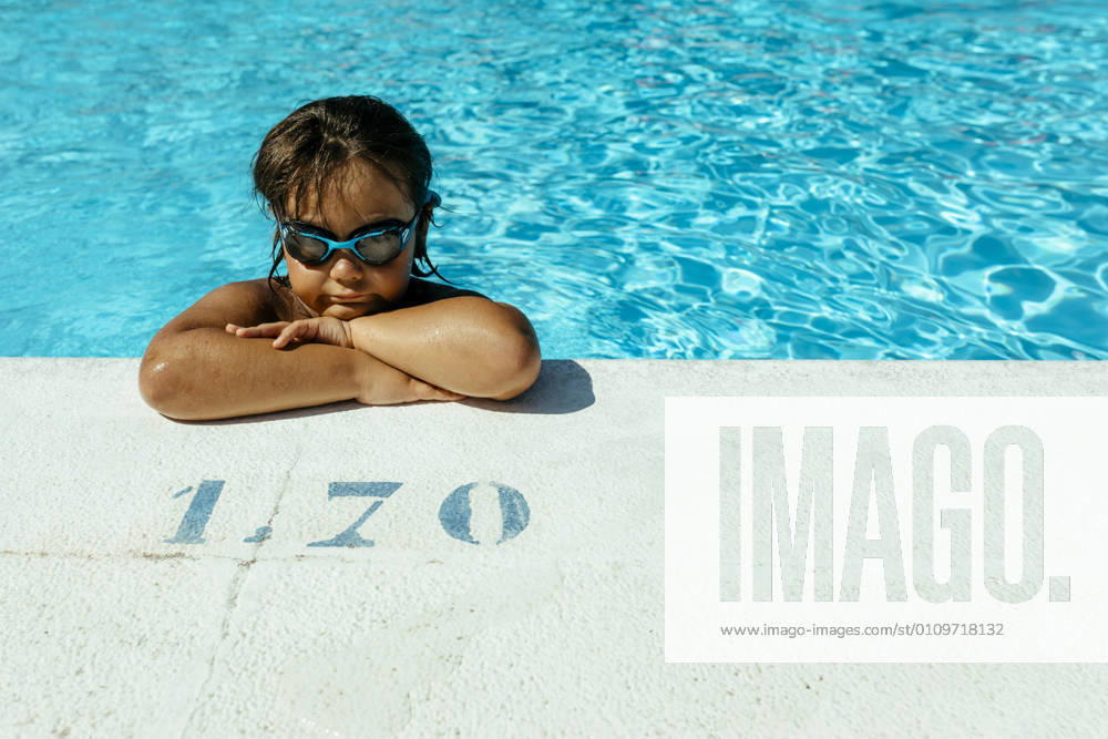 Cute boy with arms crossed leaning at poolside on sunny day model released Symbolfoto VABF03614