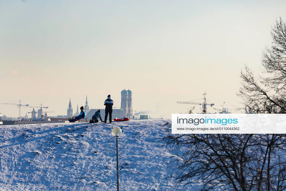 Freizeitaktivitäten im Olympiapark 15.01.2021 MÜNCHEN Schlittenfahrer auf dem Olympiaberg - Im Hintergrund die Skyline von München, inklusive Frauenkirche. München Bayern Deutschland