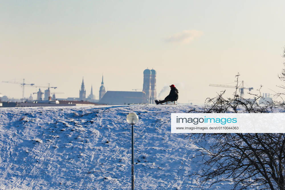 Freizeitaktivitäten im Olympiapark 15.01.2021 MÜNCHEN Schlittenfahrer auf dem Olympiaberg - Im Hintergrund die Skyline von München, inklusive Frauenkirche. München Bayern Deutschland