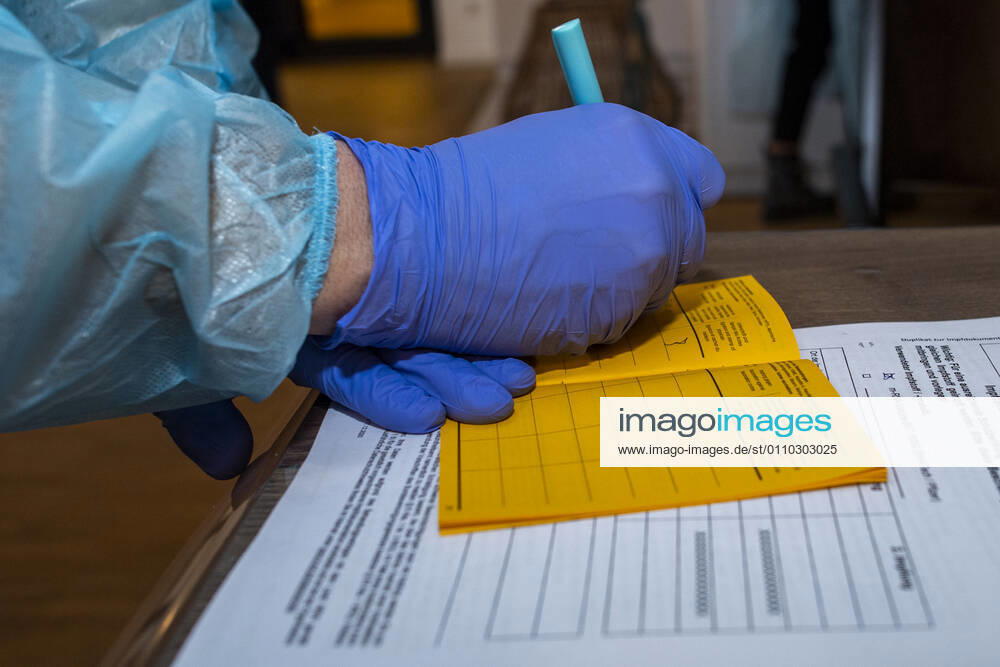 Corona-Schutzimpfung in einem Seniorenheim Ein Arzt notiert in dem amtlichen Impfausweis die Nummer der Charge mit dem Impfstoff. In einem Seniorenheim werden die Bewohner gegen eine Infektion mit dem Coronavirus geimpft. Für den Aufbau des Impfschutzes sind mit dem mRNA-Impfstoff von BioNTech zwei Impfungen im Abstand von 21 Tagen notwendig. Rietberg Nordrhein-Westfalen Deutschland
