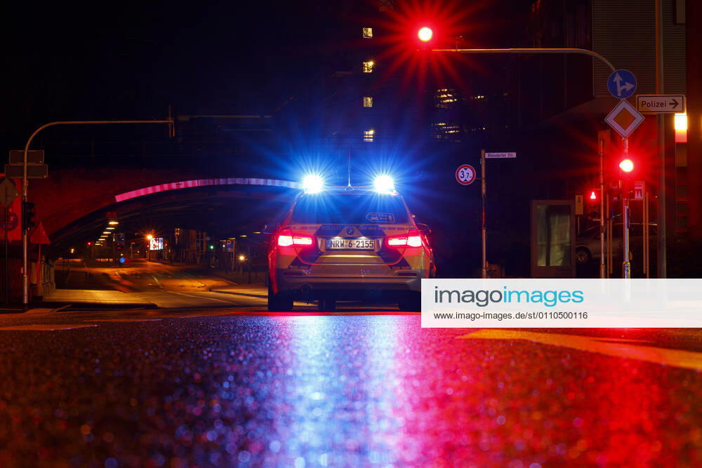 Ein Polizeiauto kontrolliert einen Wagen an einer Ampel. (Themenbild, Symbolbild) Köln