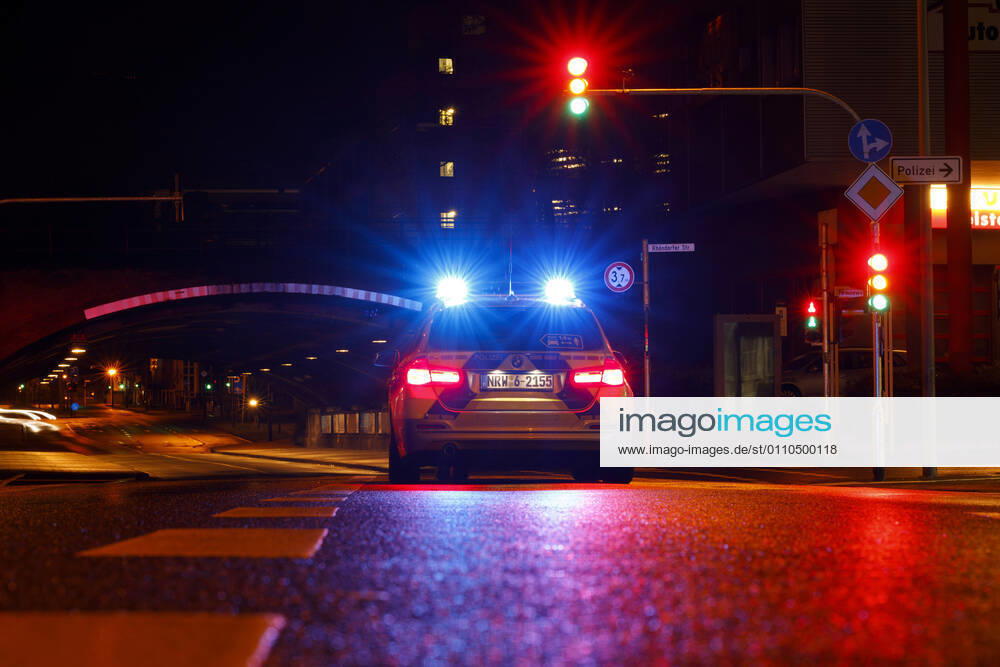 Ein Polizeiauto kontrolliert einen Wagen an einer Ampel. (Themenbild, Symbolbild) Köln
