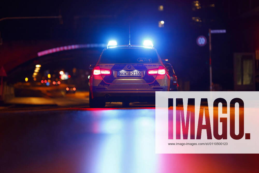 Ein Polizeiauto kontrolliert einen Wagen an einer Ampel. (Themenbild, Symbolbild) Köln