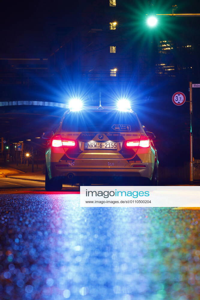 Ein Polizeiauto kontrolliert einen Wagen an einer Ampel. (Themenbild, Symbolbild) Köln