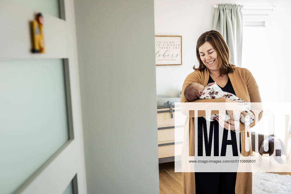 Smiling mother carrying newborn baby while standing in nursery model released Symbolfoto property released AWAF00013