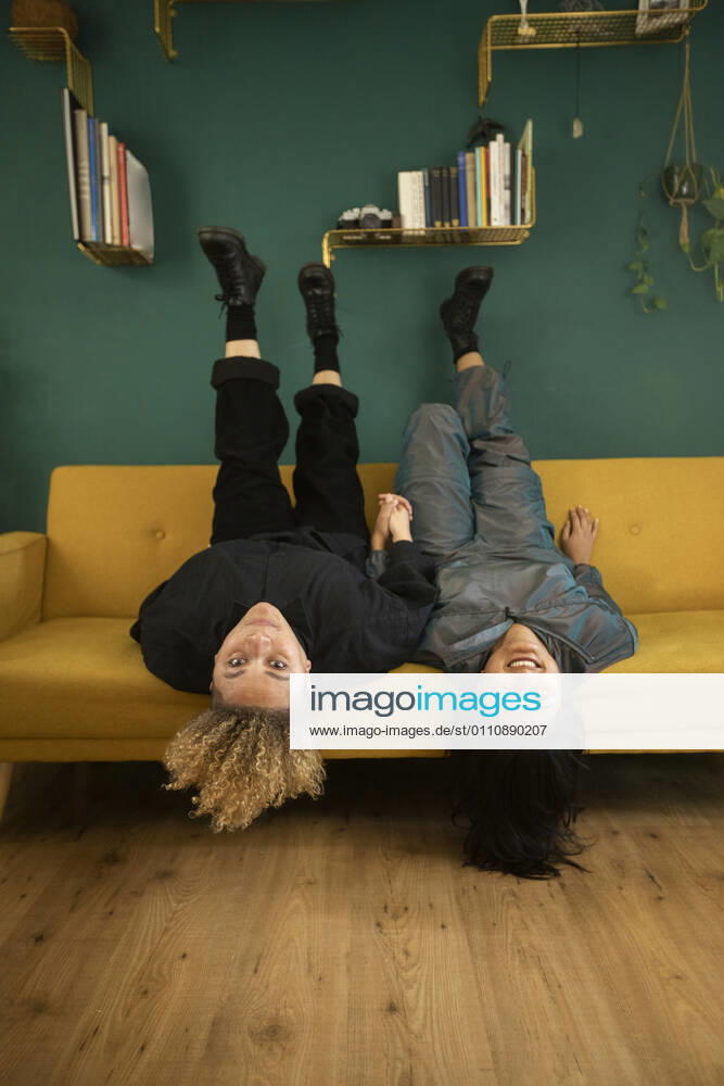 Portrait of lesbian couple lying upside down on sofa model released Symbolfoto property released AXHF00075