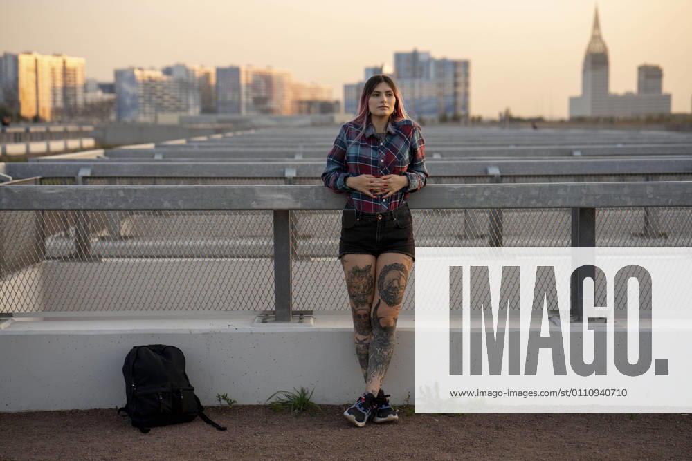IMAGO Creative, Urban Lifestyle IMAGO Kreativ: Urbane Kultur - Sommer auf den Dächern Fashionable woman day dreaming while leaning on railing at rooftop during sunset model released Symbolfoto VPIF03383