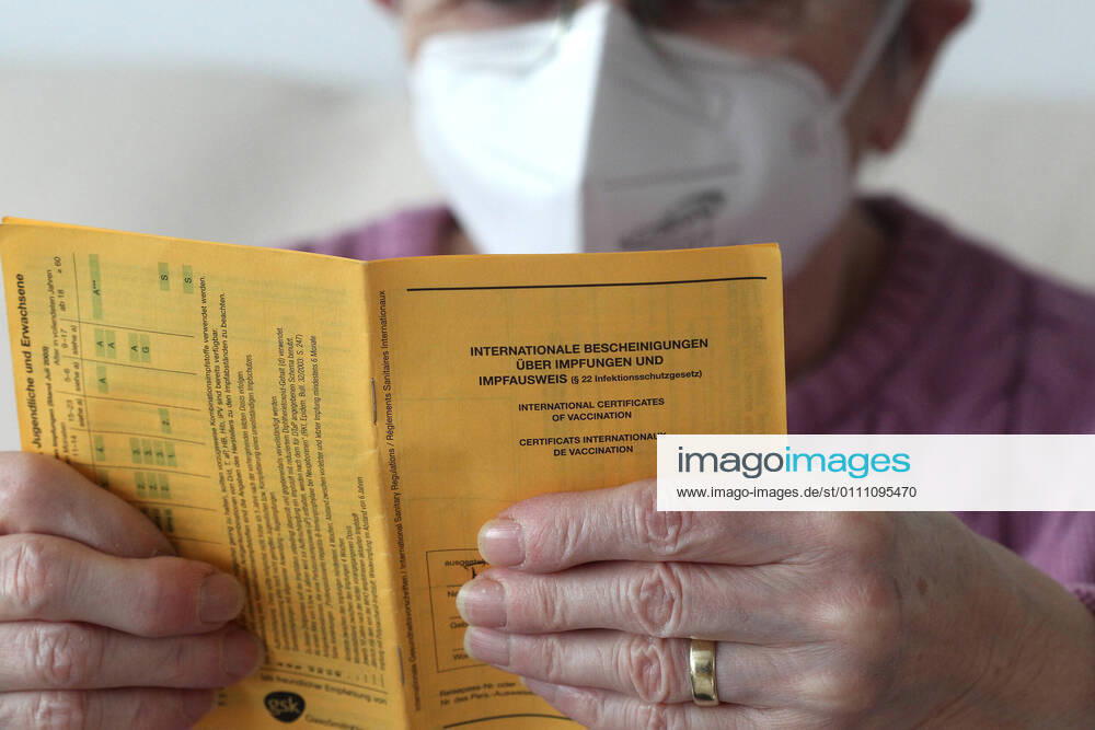 Winden Themenbild - Coronavirus, Coronapandemie - Patientin einer Risikogruppe mit internationale Impfbescheinigung, Prophylaxebescheinigung, Impfpass, Impfbuch Themenbild - Coronavirus, Coronapandemie - Patientin einer Risikogruppe mit internationale Impfbescheinigung, Prophylaxebescheinigung, Impfpass, Impfbuch Coronavirus, Coronapandemie - Impfpass, Impfbuch, Impfbescheinigung, Impfdokument, internationale Impfbescheinigung, Prophylaxebescheinigung. Eine ältere Person, Rentnerin, einer Risikogruppe, mit 80 Jahren, sitzt in ihrem Wohnzimmer auf der Couch, Sofa und hält ihren gelben Impfpass für die bevorstehende Corona Schutzimpfung in der Hand, in den älteren, runzligen Fingern ihrer Händen. Model release Vertrag liegt vor. Model
