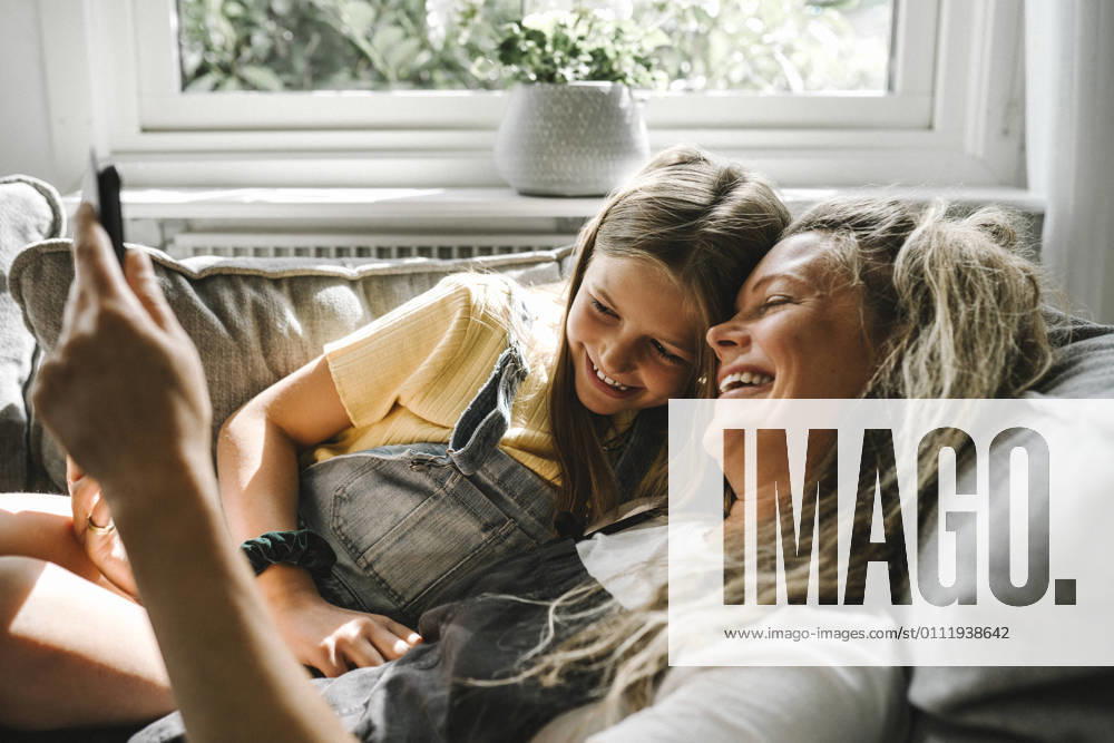 Smiling mother and daughter using digital tablet in living room Sweden, Gothenburg, model released, property released