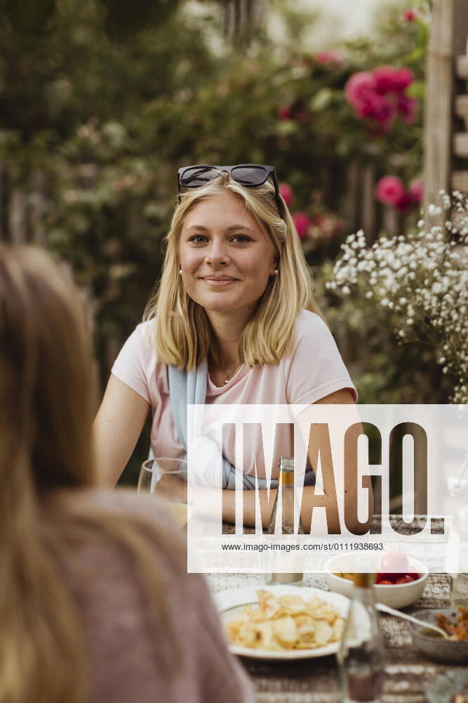 IMAGO Creative: Landleben - Essen IMAGO Creative: Landleben - Alfresco, Draußen Smiling teenage girl sitting with food at table during dinner party Sweden, Gothenburg, model released, property released