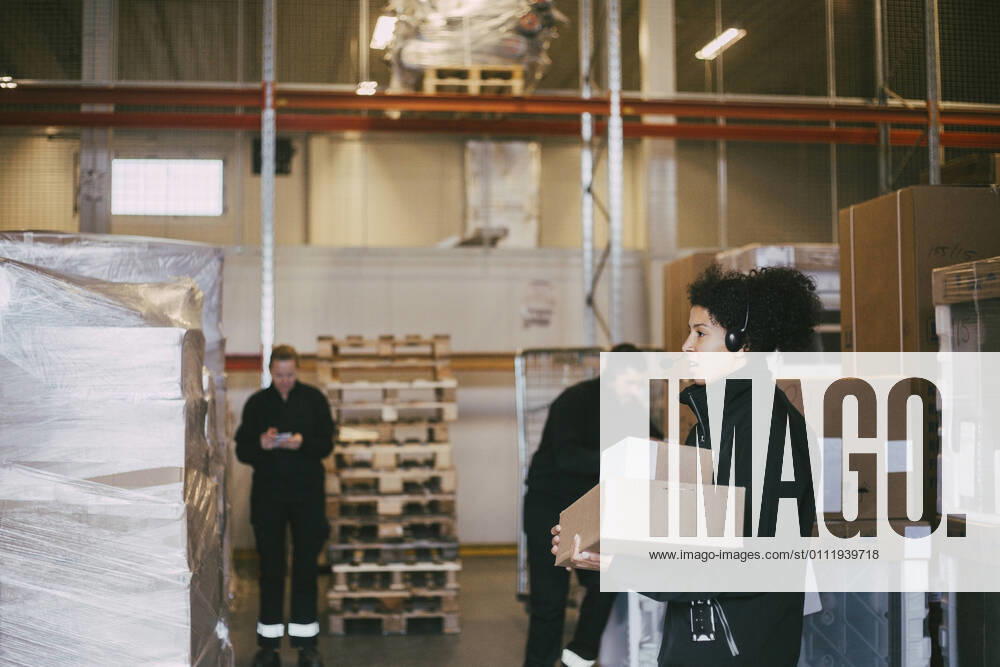 IMAGO Creative: Kreative Renaissance -- der junge Entrepreneur Female entrepreneur holding packages standing by colleagues at logistics warehouse Sweden, Stockholm, model released, property released