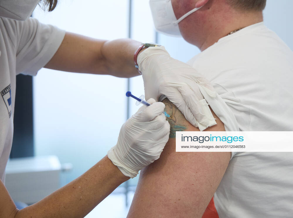 Impfung eines Mannes mittleren Alters, Impfung erfolgt in eine ungefärbte Stelle in einem Tattoo, Bayerisches Impfzentrum Augsburg, Presseführung; Bayerisches Impfzentrum Augsburg, Presseführung;