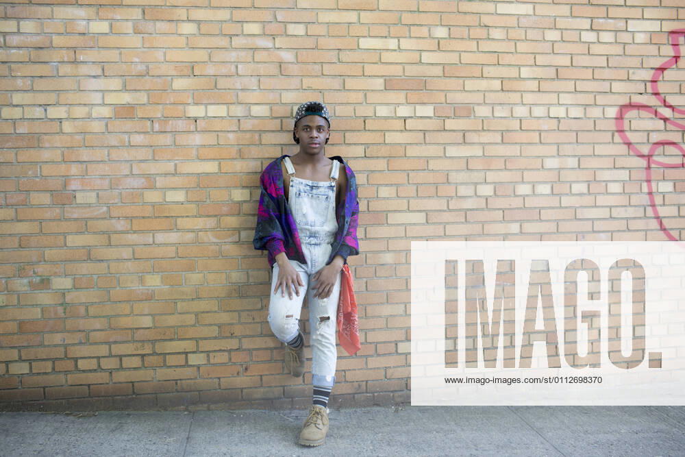 IMAGO Creative: Pride Month 2022, Engagement der Jugendlichen Young man in denim overalls posing on a brick wall model release HEX17017_TP_3216
