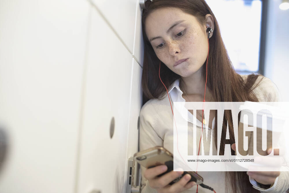 Young woman having a conversation on her smart phone holding a coffee cup in an office. model release HEX17003_TP_9404
