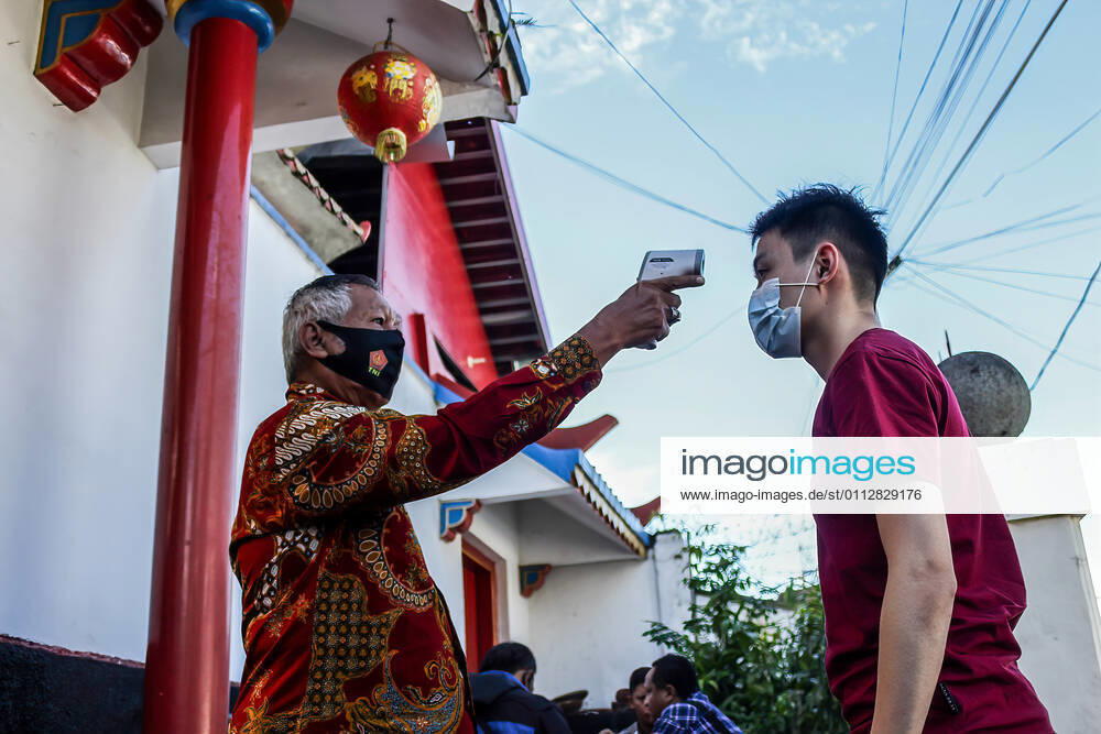 A Temple staff checks the body temperature of a man at the Dharma Ramsi Temple during the Lunar New Year celebrations..The Lunar New Year, also known as Spring Festival, falls on 12 February 2021, marking the beginning of the Year of the Ox. Bandung Indonesia - ZUMAs197 20210212_zaa_s197_070