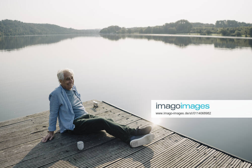 Smiling man looking away while relaxing on pier model released Symbolfoto GUSF05150