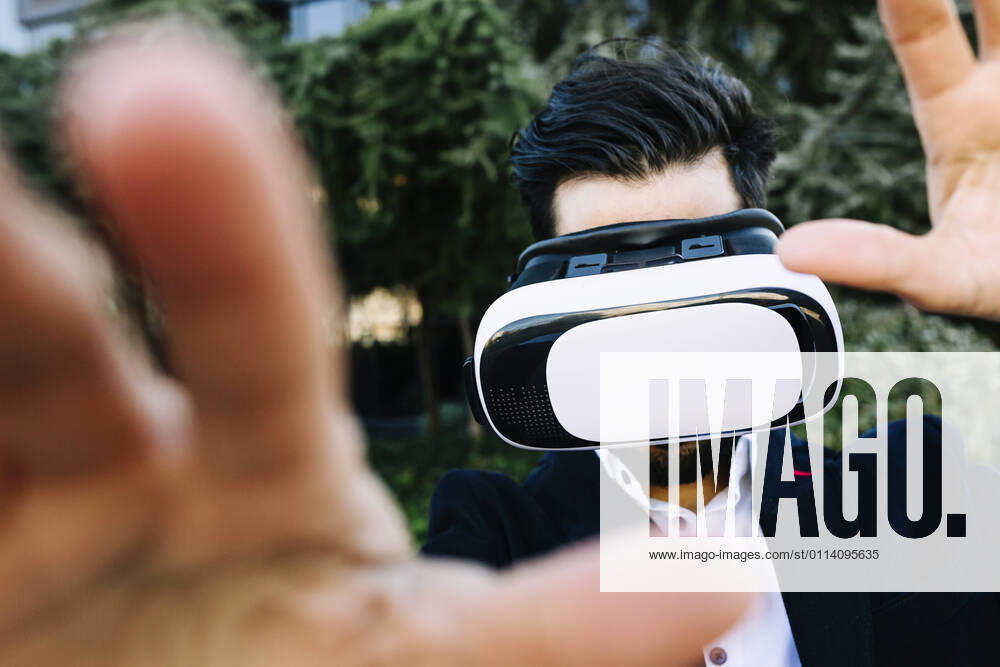 Businessman wearing virtual reality headset stretching hand while standing outdoors model released Symbolfoto XLGF01153