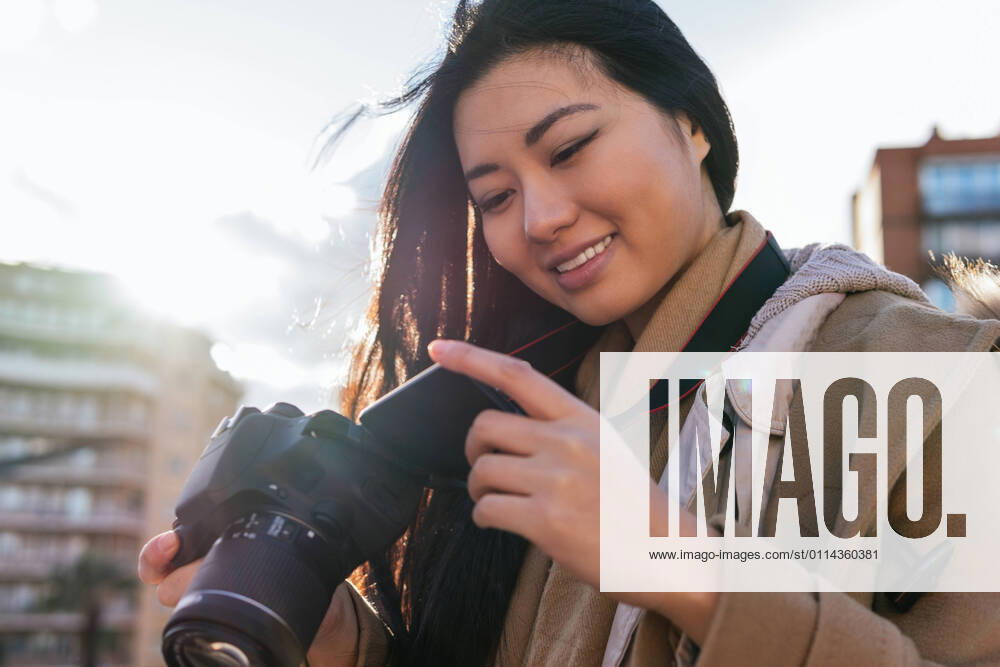 IMAGO Creative: Kreative Renaissance -- der junge Entrepreneur Ethnic young happy Asian female photographer shooting photo on professional photo camera on city street