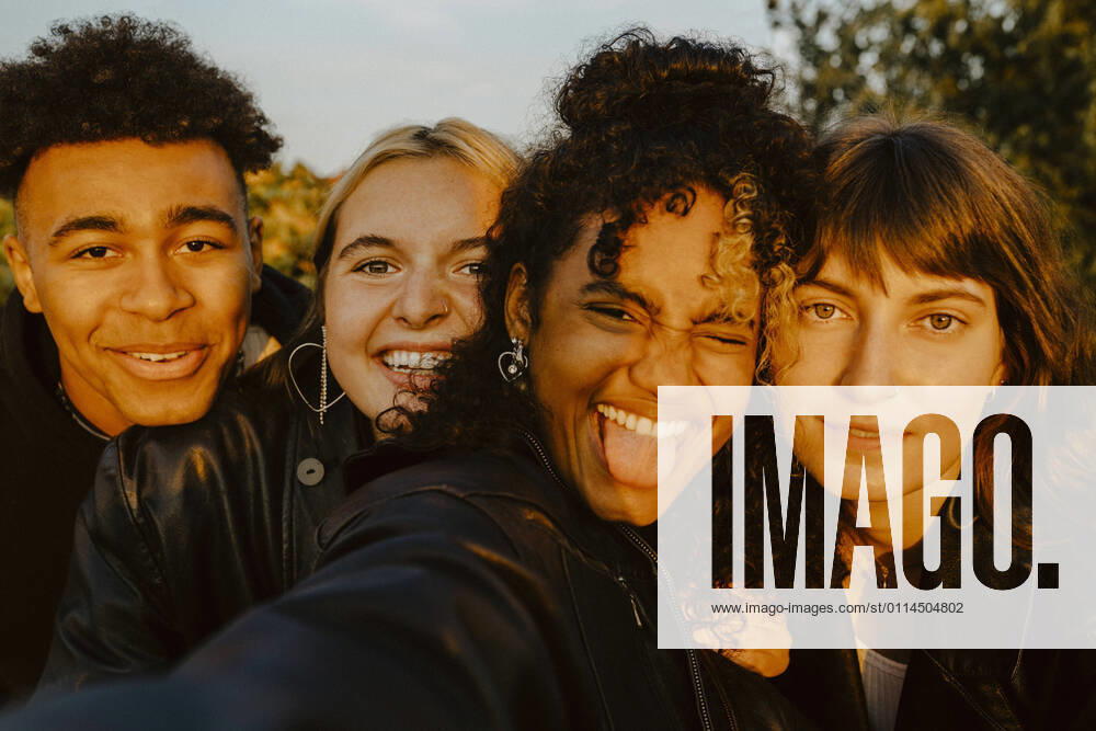 Cheerful friends taking selfie outdoors during sunset Germany, Berlin, model released