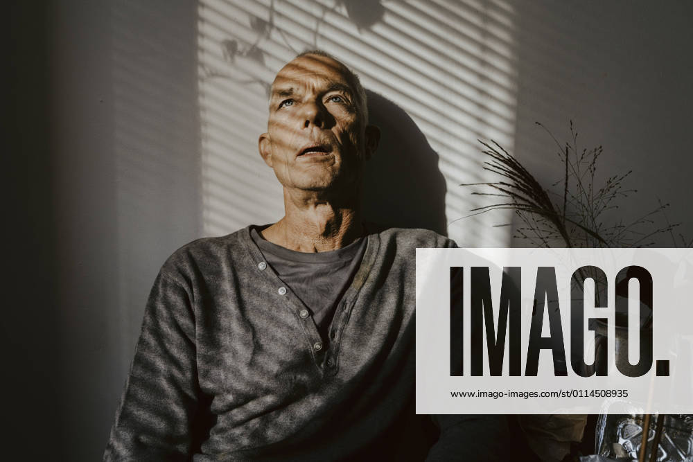 Depressed senior man against wall at home Germany, Berlin, model released, property released
