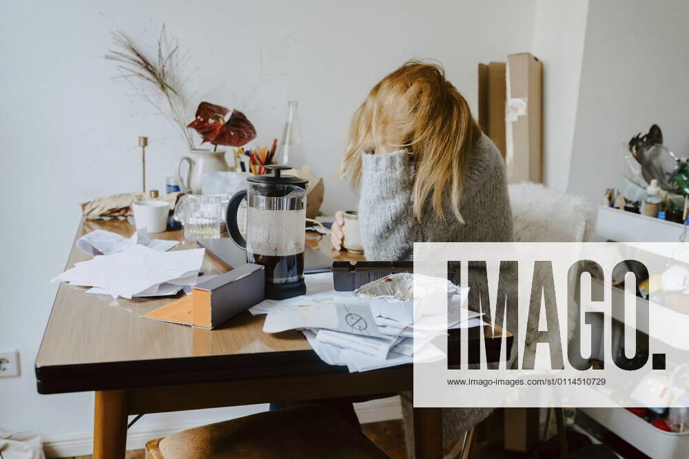 Businesswoman with mental disorder sitting on chair in living room Germany, Berlin, model released, property released