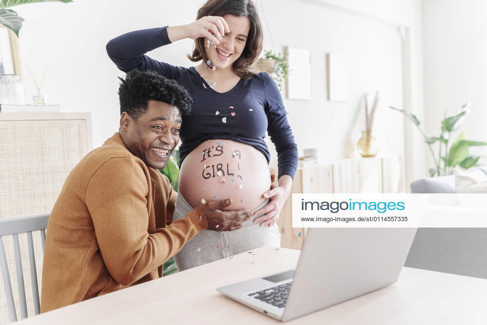 Husband and pregnant wife celebrating in front of a laptop. Parenthood concept Sant Cugat del Vallès, CT, Spain CR_KTUU210303B-639670-01 ,model released, Symbolfoto ,property released