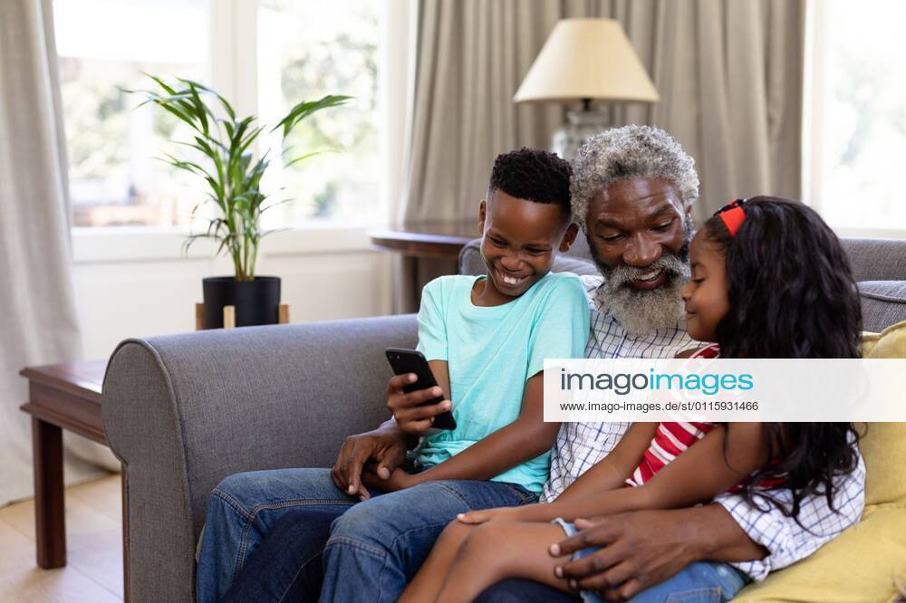 Senior African American man and his grandchildren enjoying their time at home Senior African American man and his grandchildren enjoying their time at home together, sitting on a couch, embracing, smiling, using a smartphone, model released, , property released, Cape Town, South Africa, 19.02.2020, 1340051.jpg, people,family,grandfather,granddad,granddaughter,grandson,siblings,brother,sister,childhood,together,closeness,interacting,sitting,couch,holding,using,phone,mobile phone,smartphone,connection,communication,real people,home,house,domestic life,lifestyle,enjoying,free time,leisure,relaxing,weekend,summer,sunny,love Child,Girl,Female,Mixed-Race,Boy,Male,Black,Mid Adult,Man Indoors,Side view,Day,Three Quarter Length
