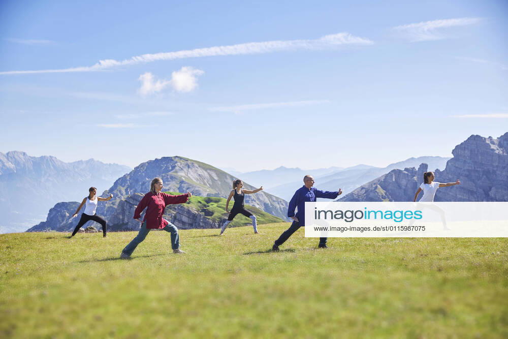 Man and women practicing yoga on meadow against sky model released Symbolfoto CVF01667