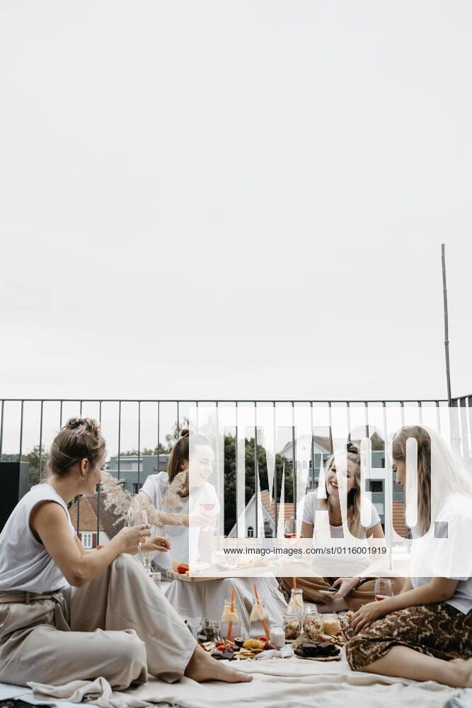 IMAGO Creative: Jahreszeit Frühling, Picknick Friends enjoying adundant picnich on rooftop trerrace model released Symbolfoto property released LHPF01411