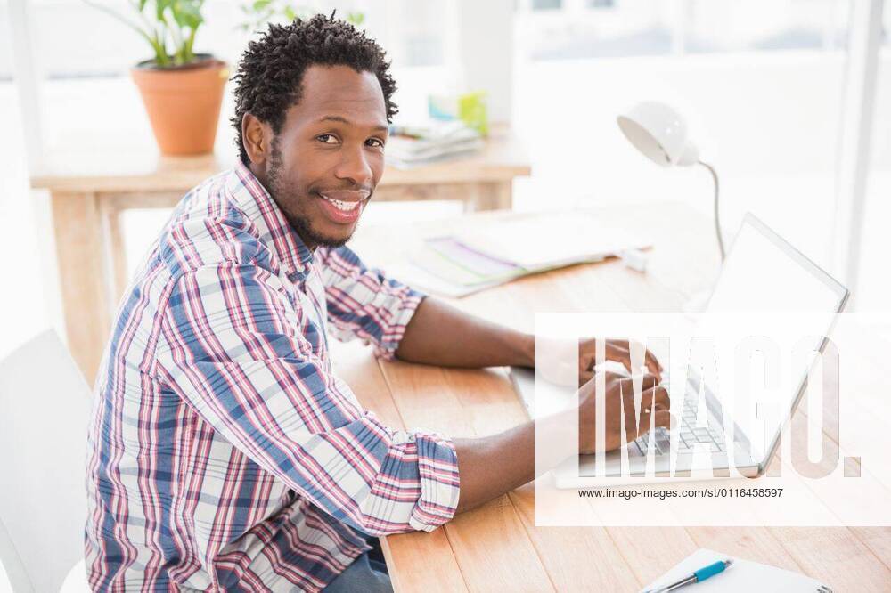 Smiling young businessman in front of the laptop Smiling young businessman in front of the laptop looking at the camera in the office, model released, Cape Town, South Africa, 30.04.2015, 550508.jpg, creative, business, casual, cool, design, designer, studio, office, job, profession, professional, career, occupation, brainstorm, brainstorming, hip, briefing, style, design professional, brown eyes, dark eyes, short hair, brunette, brown hair, plants, laptop, typing, happy, smiling, cheerful 20s, Young Adult, Man, Male, Mixed-Race, 20-24 Years, Young Men, Mixed-Race Person