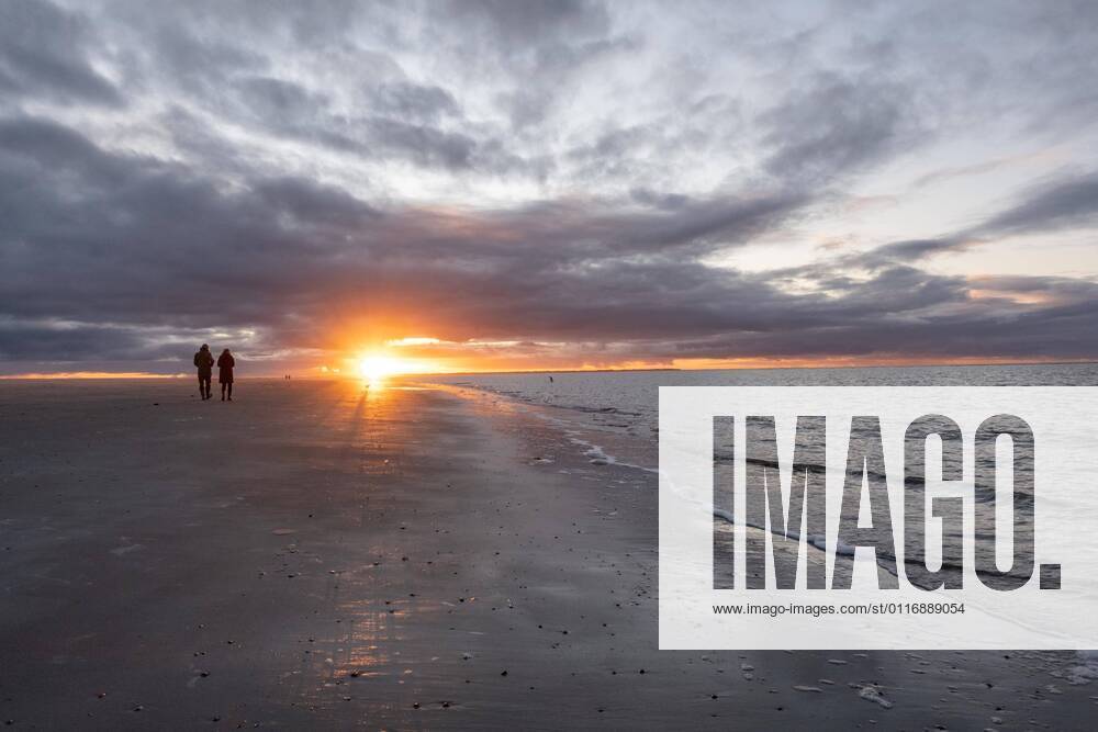 Menschen spazieren bei Sonnenuntergang am Strand, Langeoog, Ostfriesische Inseln, Niedersachsen, Deutschland, Europa
