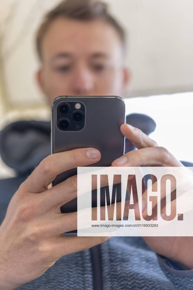 Junger Mann tippt auf, hält iPhone 11 Pro, Smartphone