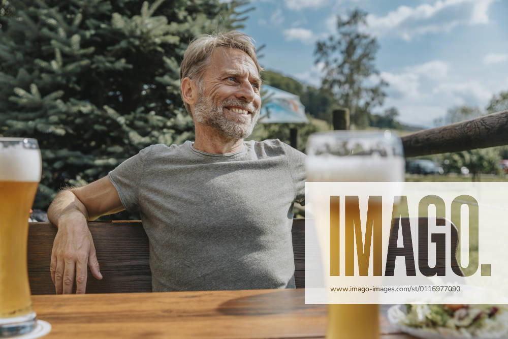 Smiling mature man looking away while sitting in beer garden model released Symbolfoto MFF07644