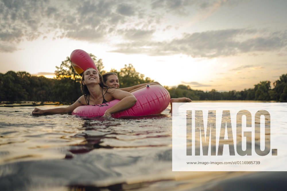 Friends having fun on a lake on a pink flamingo floating tire model released Symbolfoto GUSF02325