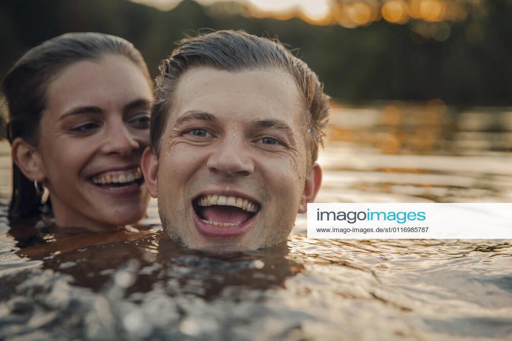 Young couple swimming in lake at sunset model released Symbolfoto GUSF02365