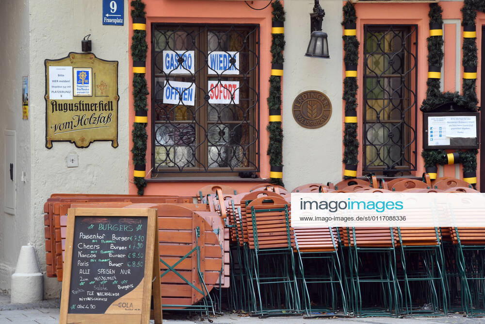 Themenbild: Coronavirus Pandemie Folgen fuer die Gastronomie: GASTRO WIEDER OEFFNEN SOFORT Im Fenster eines bayerischen Restaurants in Muenchen fordern die Eigentuemer die sofortige Oeffnung der Gastronomie. Uebereinander gestapelte Stuehle und Tische lehnen an der Hauswand.