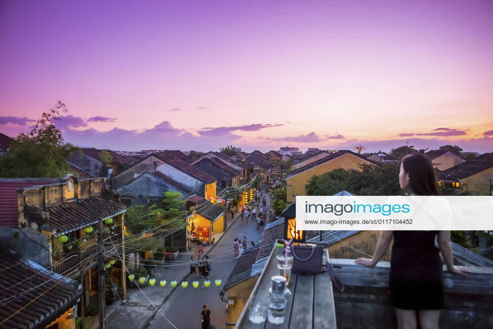 IMAGO Creative: Urbane Kultur - Sommer auf den Dächern Tourists walk down the colonial streets in historic old town Hoi An. Chinese lanterns illuminate the walkways as tourists watch the sunset from a rooftop restaurant; Hoi An, Quang Nam, Vietnam