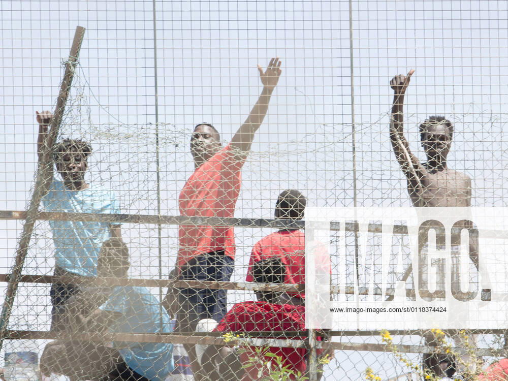 Several migrants behind a fence at the Ciudad del Altos del Real football stadium on May 18, 2021, in Melilla, Spain. A total of 86 migrants of sub-Saharan origin -- 85 men and one woman -- have entered Melilla on Tuesday along the southern seawall of the nearest coast that separates the Spanish city from Morocco, hours after thousands of Moroccans entered Ceuta, in an action in which three civil guards and a woman have been injured by the aggressiveness shown by those who entered using stones. The migrants arrived today in Melilla have been transferred from the Temporary Stay Centre for Immigrants (CETI) to the Altos del Real Football City, where they are now. 18 MAY 2021;CEUTA;MIGRATION CRISIS;MELILLA;MOROCCO;SUB-SAHARAN Ãngela Rios L